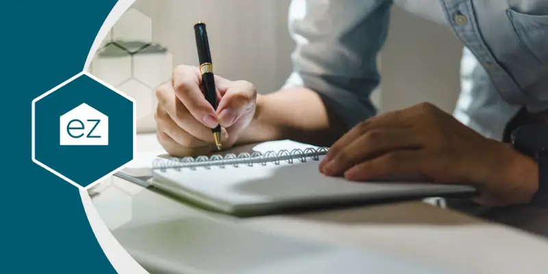 a person writing on a notebook using a pen