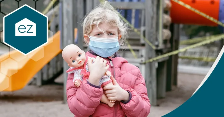 a sad girl wearing a mask while holding her doll in the playground